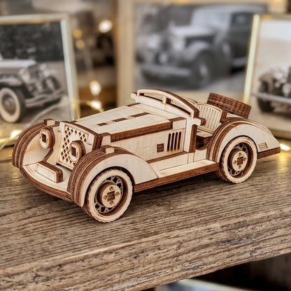 Detailed view of a vintage sport car model created from laser cut plywood, set against blurred vintage car photos.
