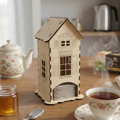 Laser cut wooden tea bag house with contrasting dark edges, scalloped base, and classic cottage design, displayed on a rustic kitchen table background.