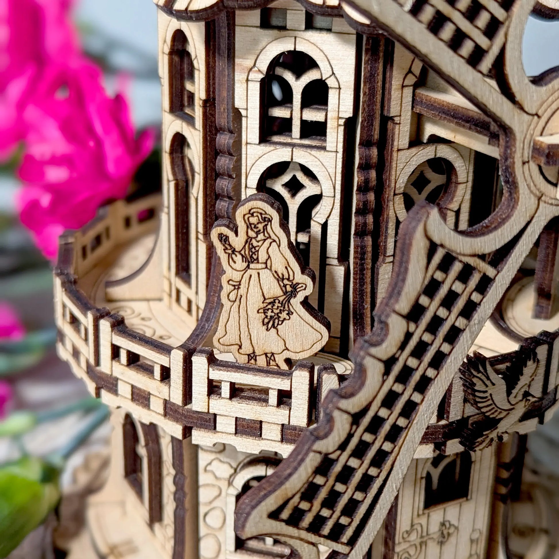 Detailed macro view of a tiny woman figurine placed onto the upper deck balcony of a laser cut plywood windmill model.