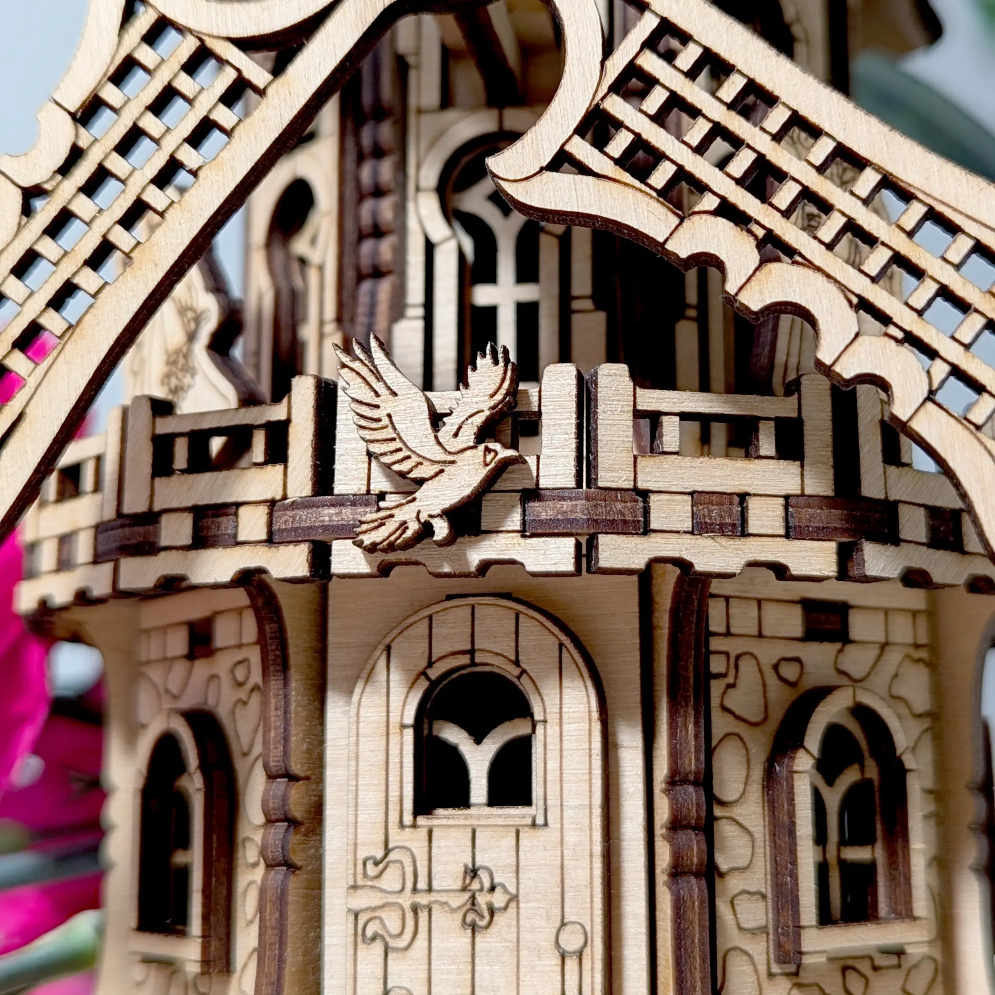Extreme close-up view of a small engraved flying bird emblem attached to a decorative laser cut plywood windmill deck.