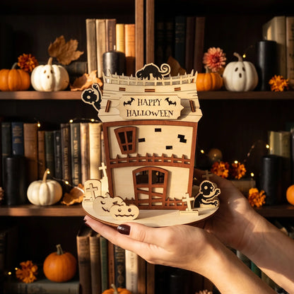 Hands holding a handcrafted laser cut plywood zombie house model against a blurred background of library shelves.