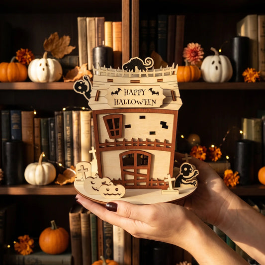 Hands holding a handcrafted laser cut plywood zombie house model against a blurred background of library shelves.