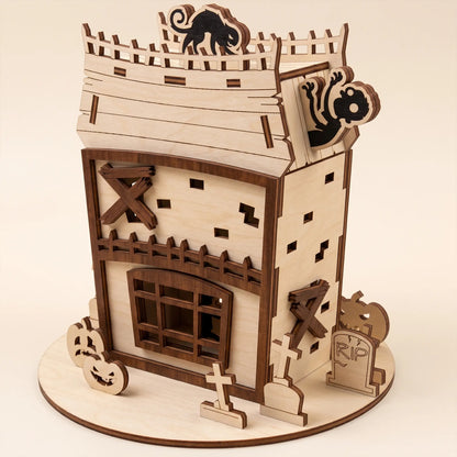 Back perspective of an intricate laser cut plywood zombie house decor with wooden fence and graveyard elements.