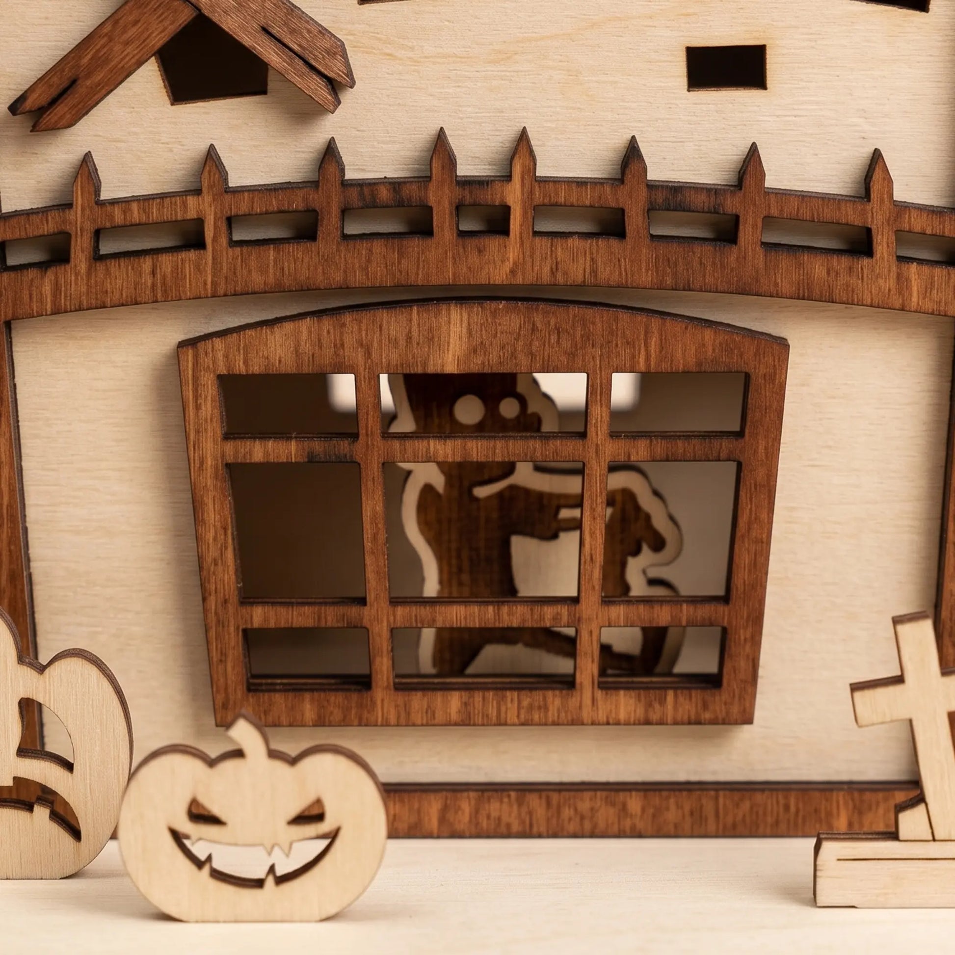 Macro detail of a laser cut plywood zombie house window, showing precise wooden craftsmanship and spooky silhouette.