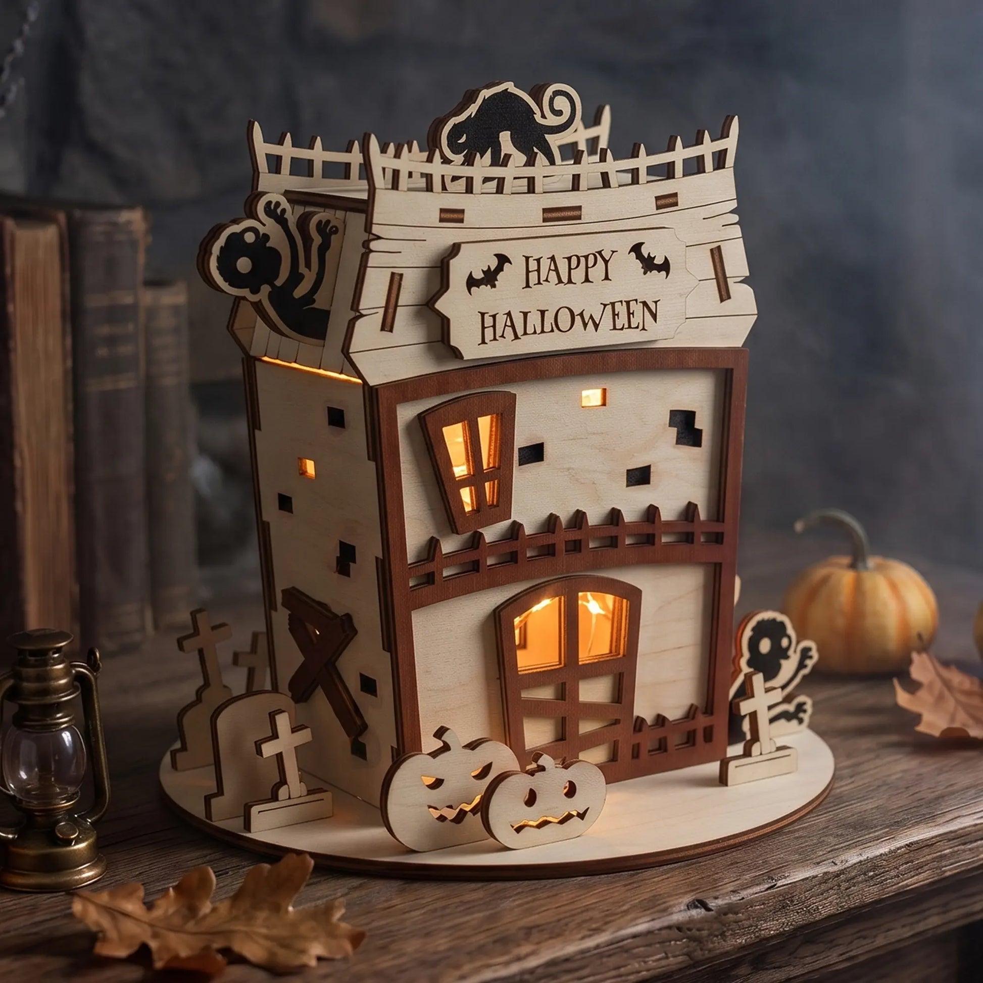 Halloween-themed laser cut plywood zombie house decoration with warm inner lighting, pumpkins, and miniature gravestones.