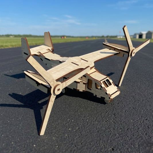 A 3D laser cut plywood tiltrotor aircraft model on an asphalt runway. High-wing design with two large rotors in airplane mode. Features interlocking wooden parts, cockpit windows, and natural wood grain with dark edges. Bright sunny day background.