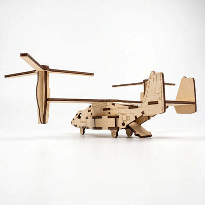 Rear side view of 3D laser cut plywood tiltrotor aircraft model with open cargo ramp and tail fins on plain white background.