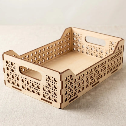 Three-quarter view of an empty single-compartment laser cut plywood tray with geometric cutout patterns on a tablecloth.