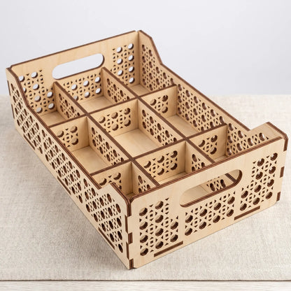 High-angle view of an empty laser cut plywood multi-compartment organizer tray sitting on a textured grey tablecloth.