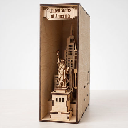 Front view of a laser-cut birch plywood USA book nook with a top label, featuring the Statue of Liberty and city skyline models.