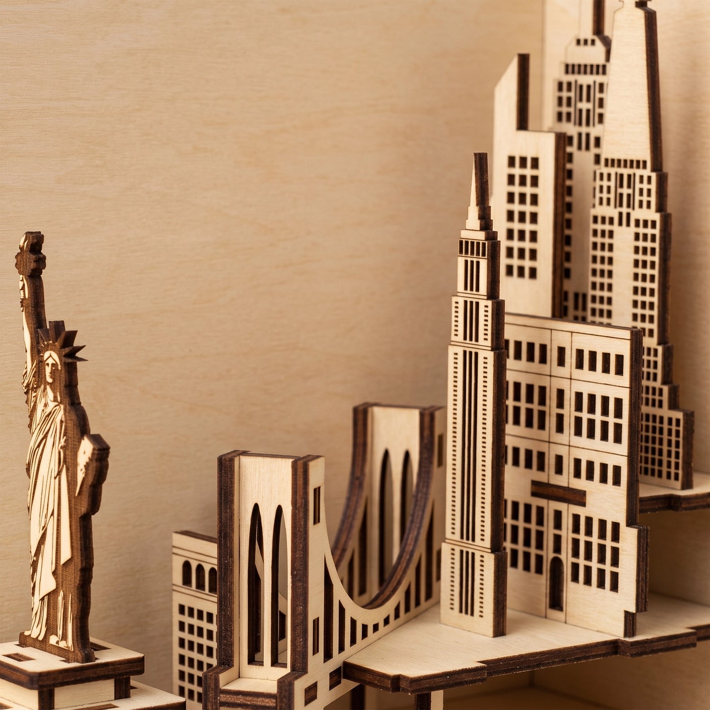 Close-up of a laser-cut birch plywood USA book nook featuring the Statue of Liberty, bridge, and skyscrapers with dark burnt edges.