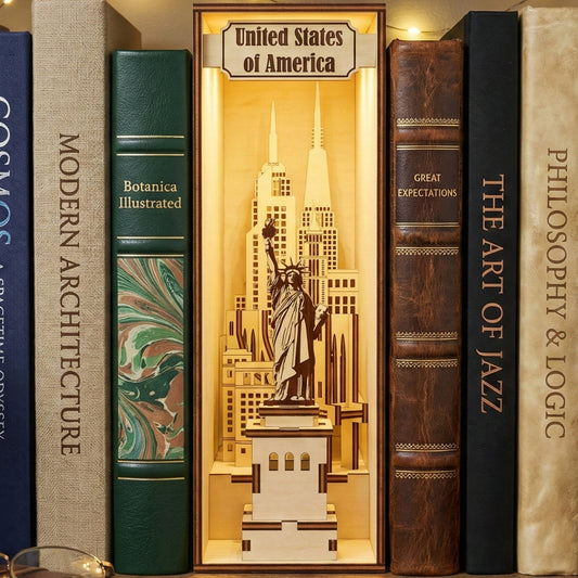 Warmly lit laser cut wooden USA Book Nook featuring the Statue of Liberty and New York City skyline, nestled between books on a glowing library shelf background.