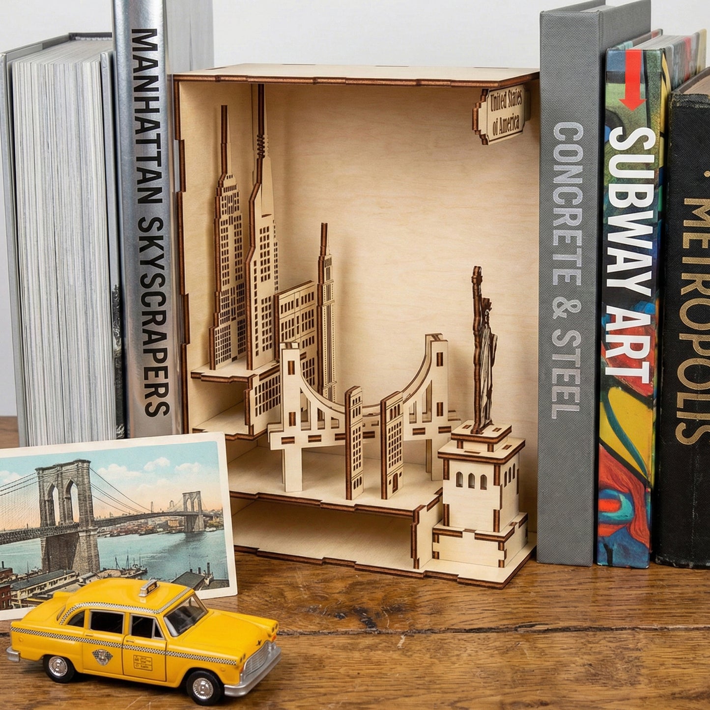 USA Book Nook architectural model of laser cut wood displayed alongside a miniature yellow taxi and skyscraper-themed books background.