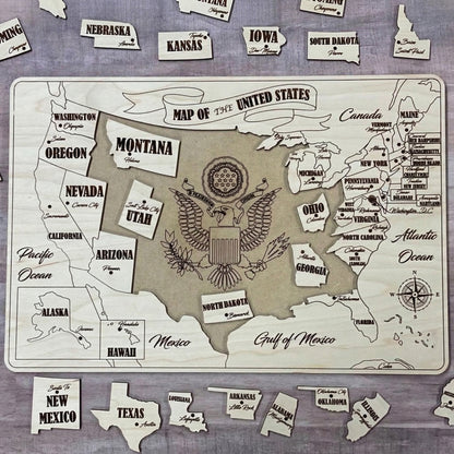 A partially assembled USA puzzle map made of laser cut plywood. Several state pieces like Texas and New Mexico are scattered around a wooden base board that features an engraved eagle crest in the center and a decorative title banner.