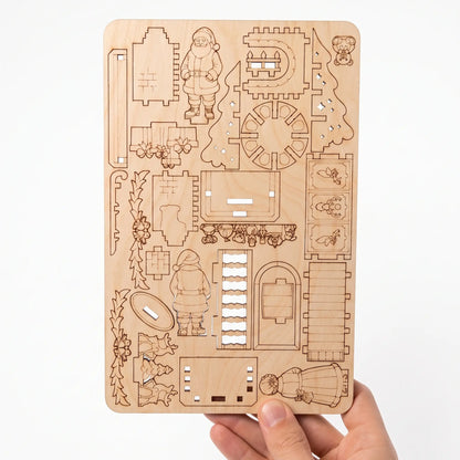 Laser-cut plywood sheet held in hand with model parts arranged in a compact nesting layout