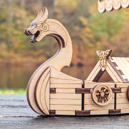 Close-up of the dragon head prow on a laser cut wooden Viking ship model, showing layered wood details and engraved lines.