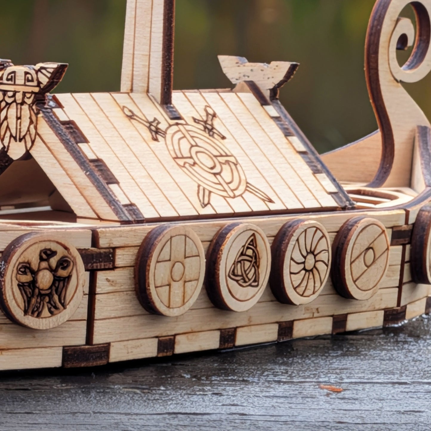 Laser cut Viking ship model with engraved shields along the sides, showing close-up detail of the shield patterns and wooden planks