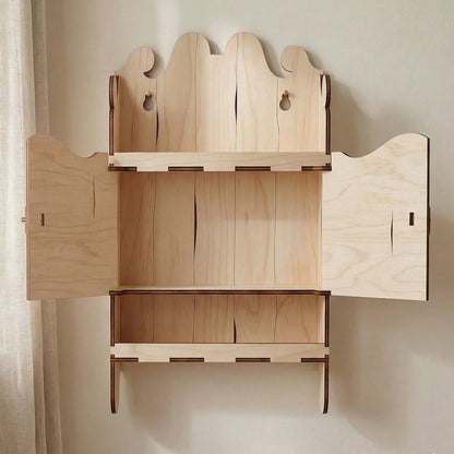 Open view of a laser cut plywood miniature wall shelf. Two doors are swung open to reveal the interior storage space. Crafted with precise interlocking joints and a decorative arched header, shown in a bright interior.