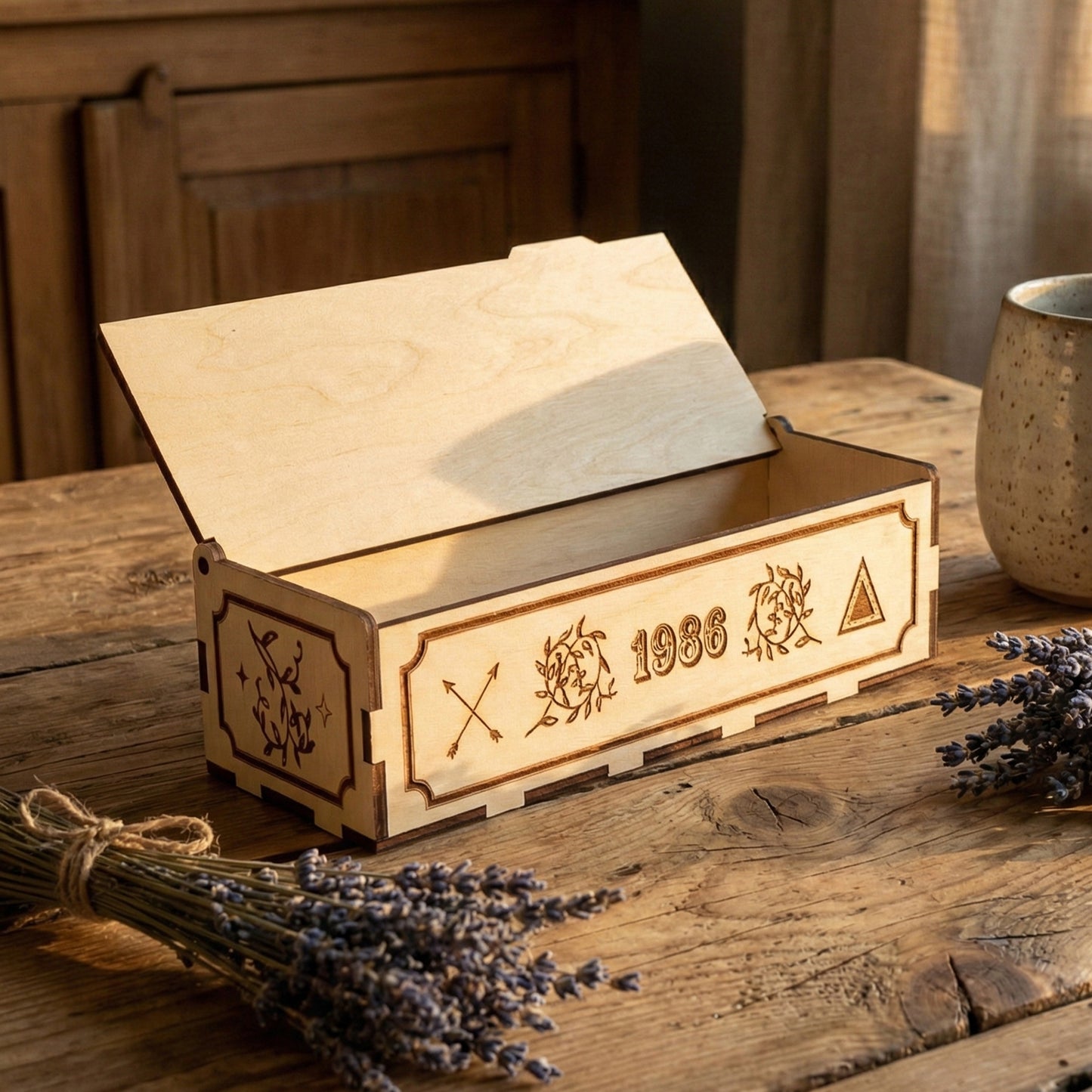 Open laser cut plywood vintage storage box with a hinged lid. Detailed engravings of arrows and floral wreaths are visible on the front. Two bundles of dried lavender sit nearby, highlighting the natural, handcrafted feel of the item.