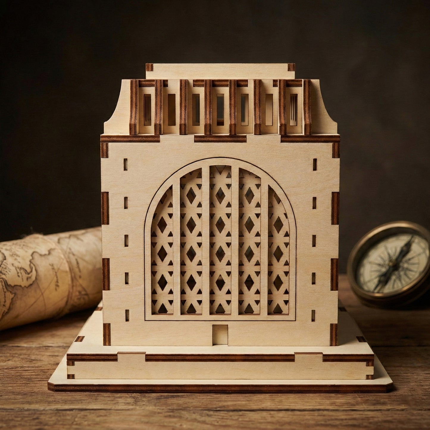 Frontal view of the Voortrekker Monument wooden model. The laser cut plywood design showcases detailed geometric lattice patterns inside the large central arch. The interlocking finger joints and layered base are clearly visible against a dark background.