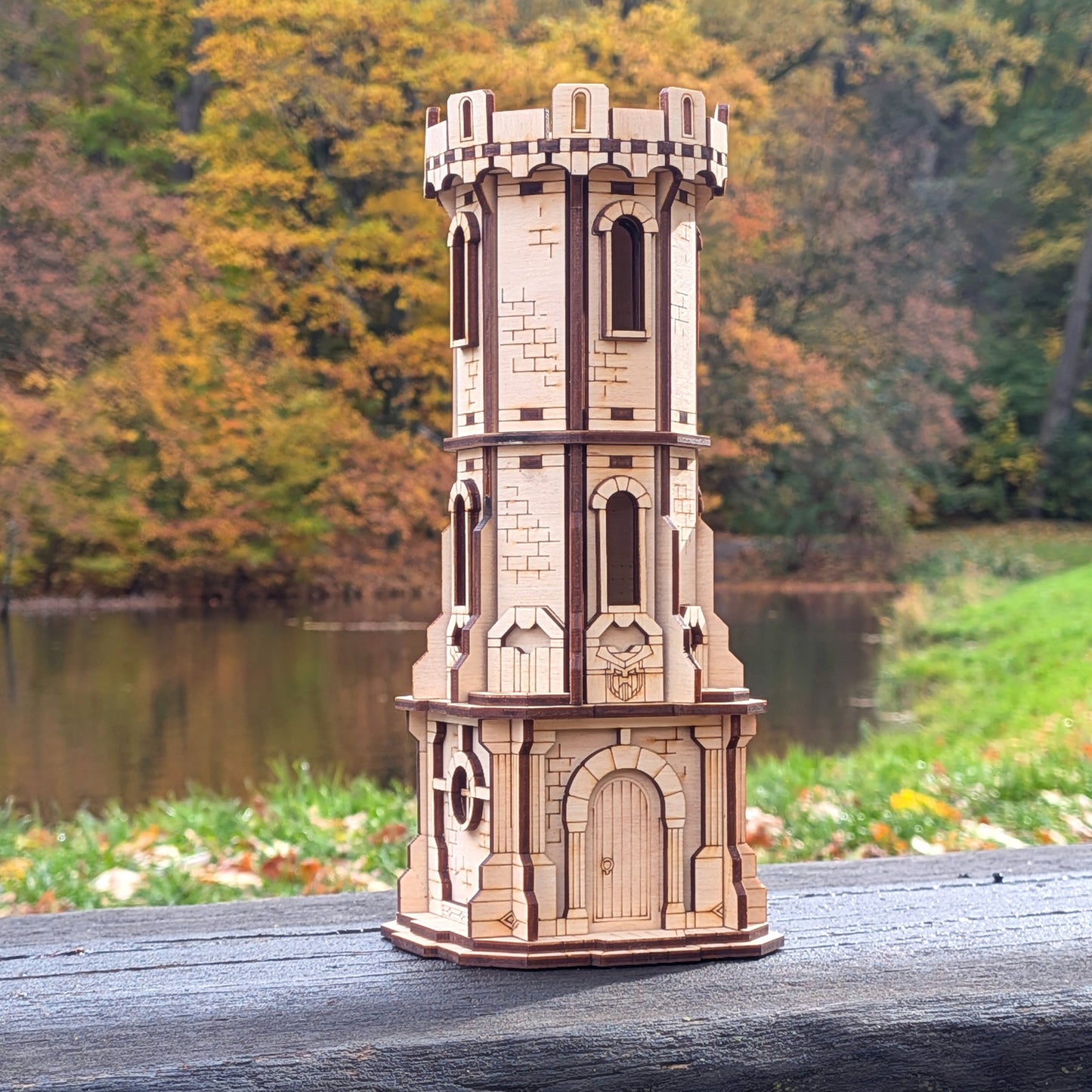Wooden laser cut model of a castle tower on a wooden surface with a natural background.
