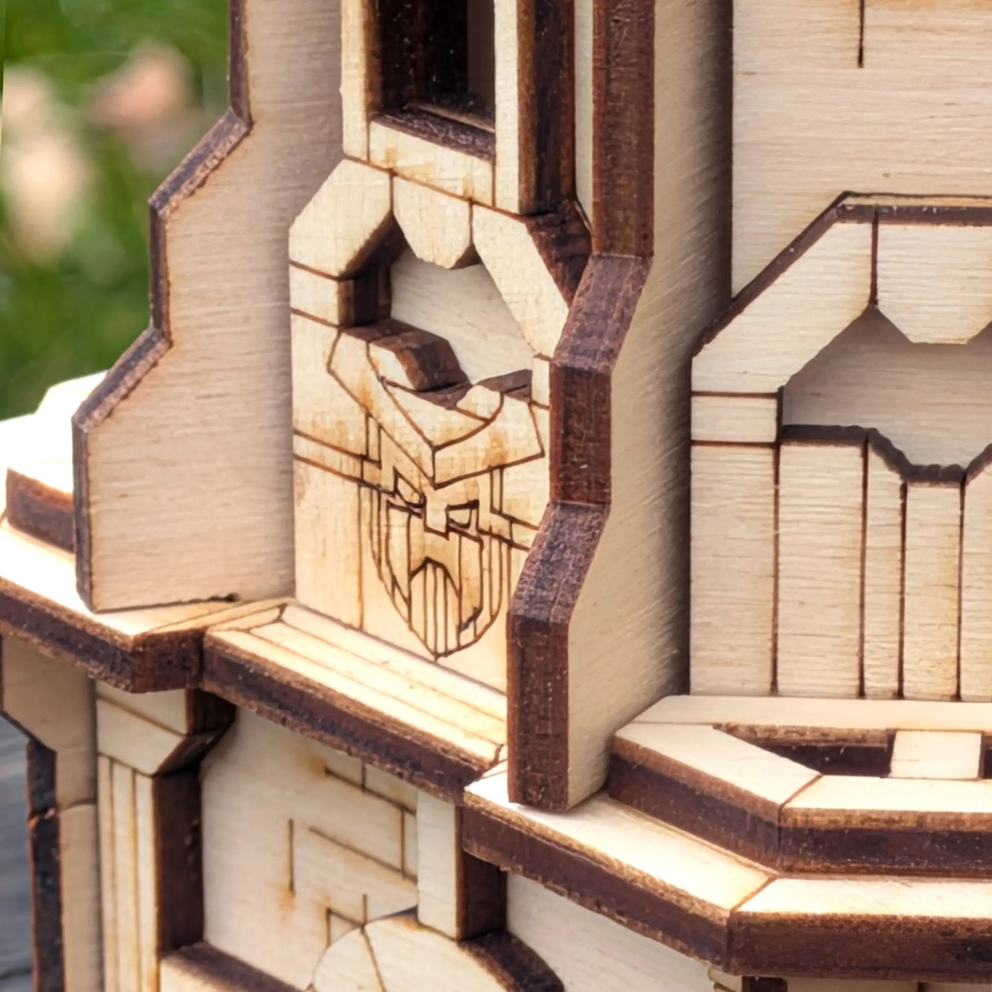 A detailed macro close-up view of an engraved decorative emblem on a miniature medieval castle tower in laser cut plywood