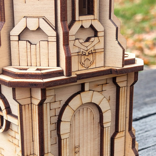 A macro close-up showing the engraved stone brick arch door and pillars of a miniature tower made from laser cut plywood