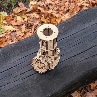 Wooden laser-cut model of a tower on a dark wooden surface with autumn leaves in the background