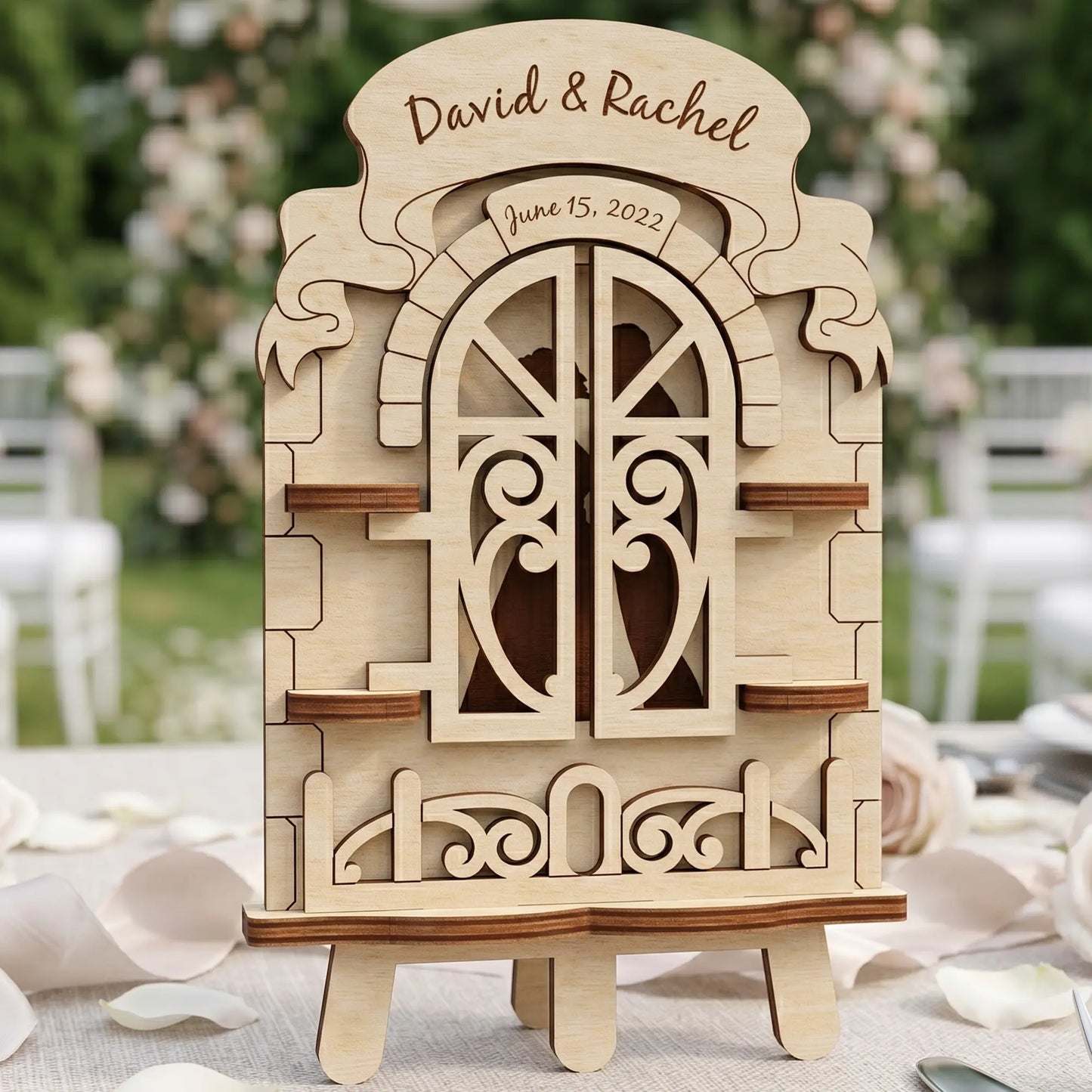 Laser cut plywood wedding window with closed heart-patterned shutters and personalized engravings on a white linen table.
