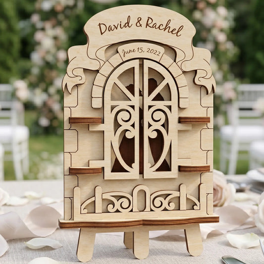 Laser cut plywood wedding window with closed heart-patterned shutters and personalized engravings on a white linen table.
