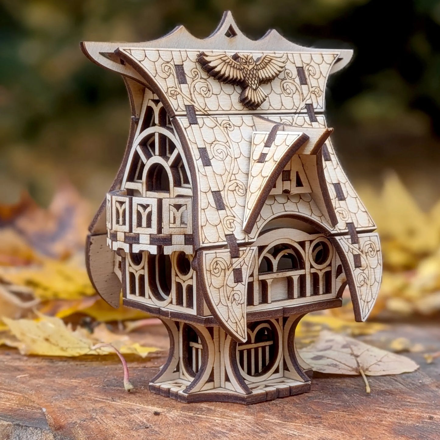 Front perspective view of an intricate miniature fairytale owl cottage on a pedestal, crafted from fine laser cut plywood.