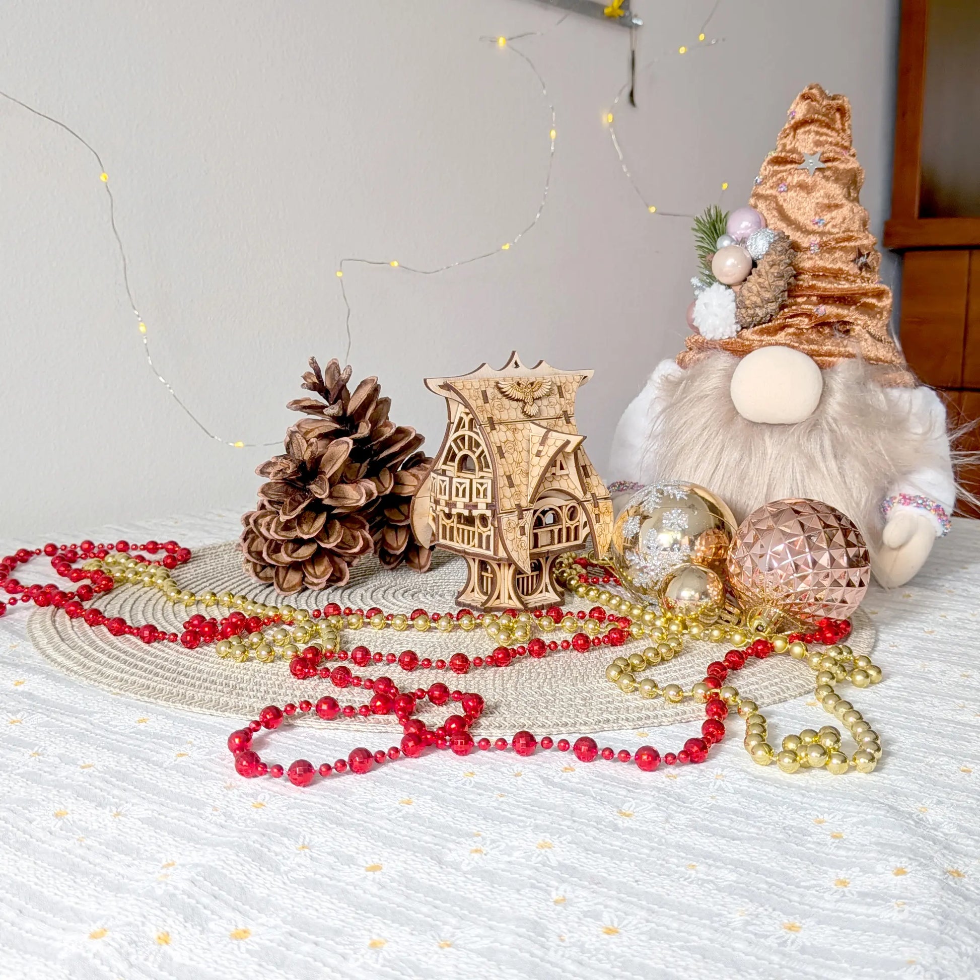 Whimsical miniature owl house made from laser cut plywood, staged on a table with a plush holiday gnome and festive beads.
