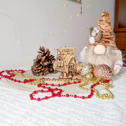 Whimsical miniature owl house made from laser cut plywood, staged on a table with a plush holiday gnome and festive beads.