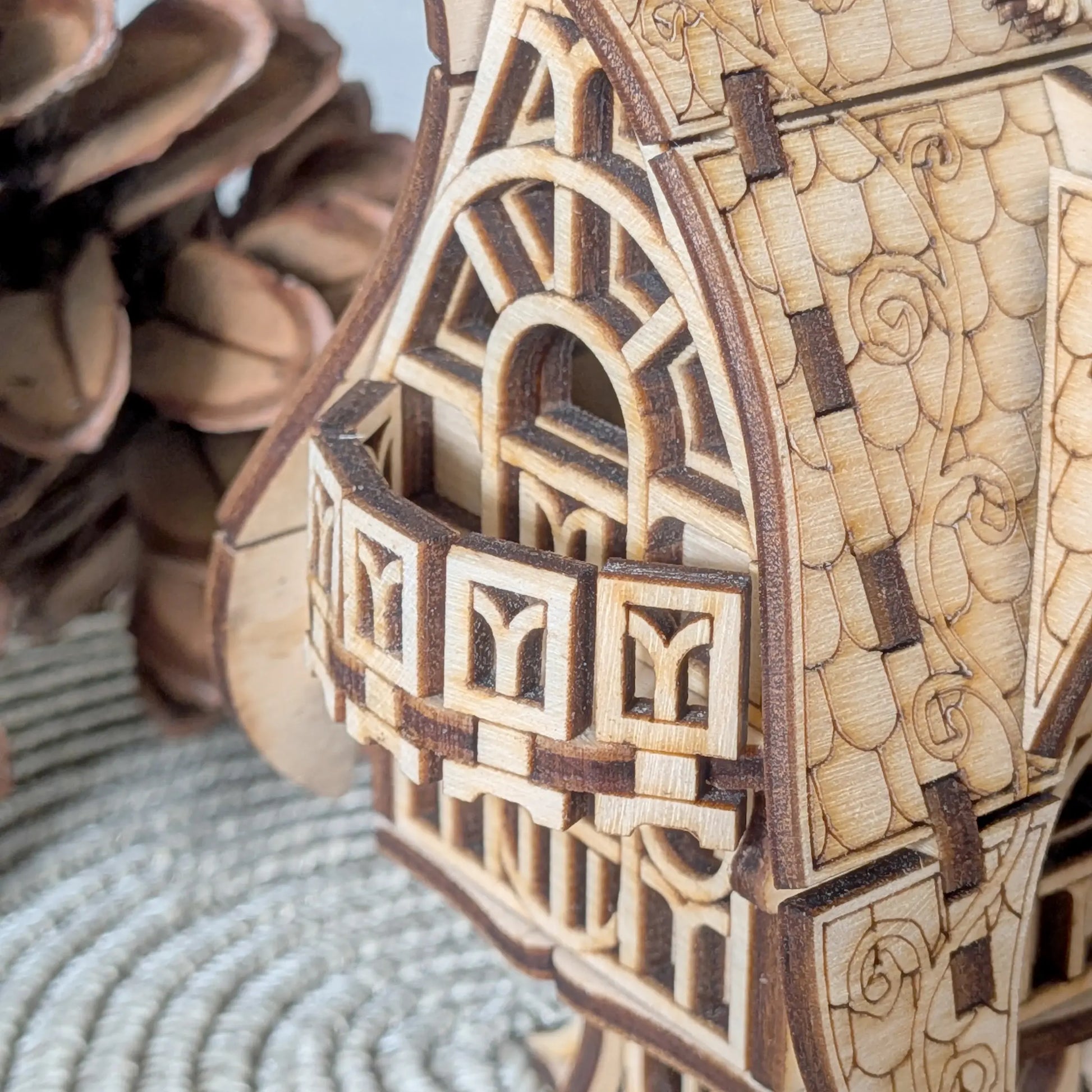 A detailed macro close-up showcasing the tiny curved balcony and window profiles of a laser cut plywood fantasy cottage.