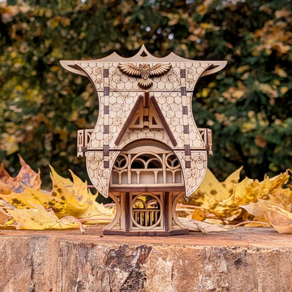 A clean straight front view of a miniature whimsical fairytale owl cottage of laser cut plywood upon a forest tree stump
