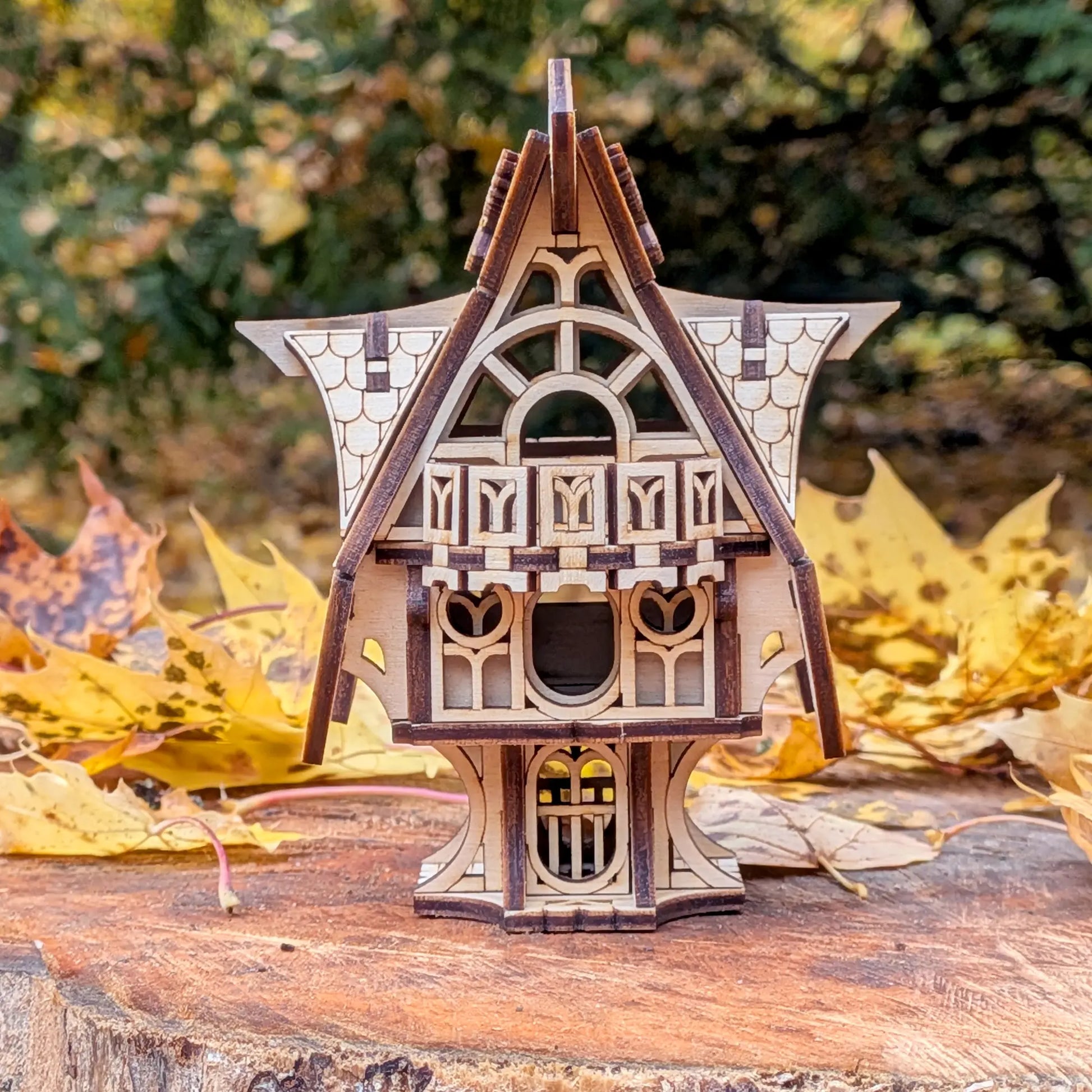A beautiful rear front elevation view of an intricate miniature fairytale house on a wooden stump, from laser cut plywood