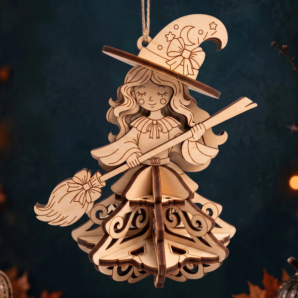 Laser cut plywood witch ornament with broom and 3D layered dress standing on dark reflective base against autumn decor.