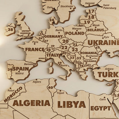 Close-up of Europe on the laser cut plywood world map. Shows detailed engraving of country names and cities like Berlin and Kyiv. Numbers represent smaller countries. Highlights precise dark burnt edges and natural light wood grain.
