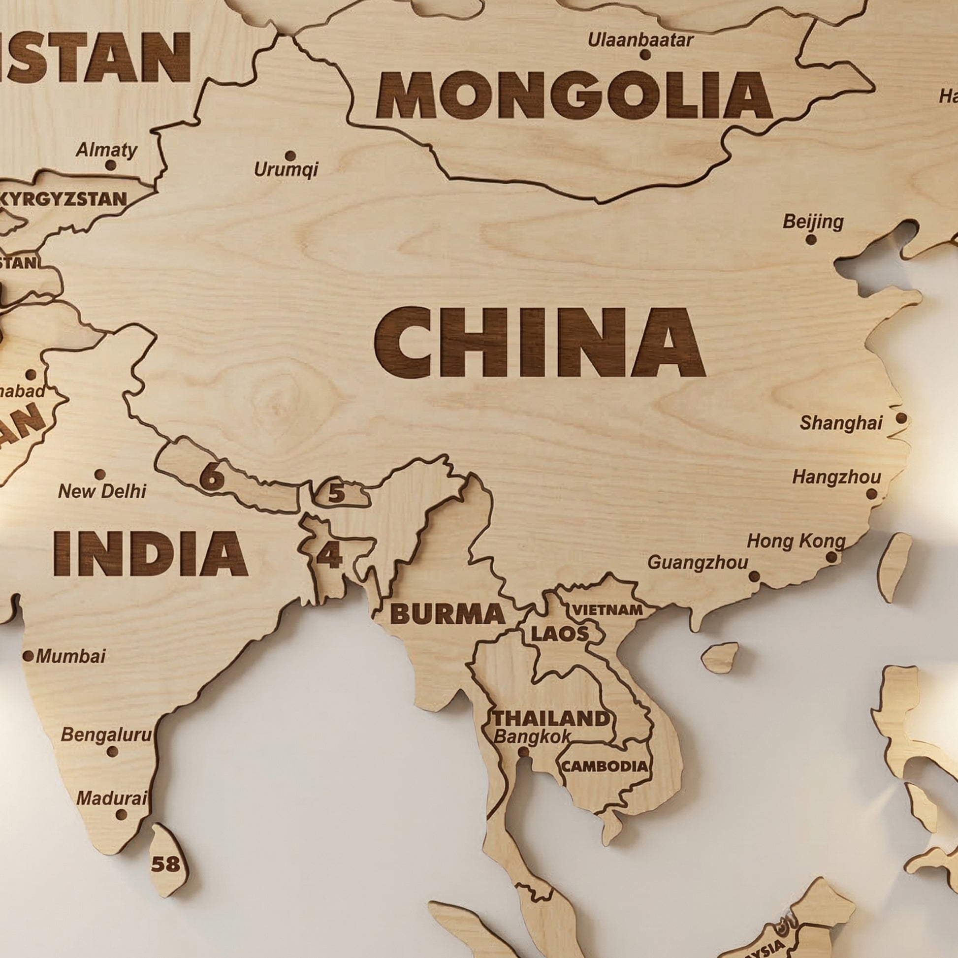 Close-up of Asia and Southeast Asia on the laser cut plywood world map. Features bold engraved country names like China and India with city dots. Precisely cut borders for Thailand, Vietnam, and surrounding islands are clearly visible.