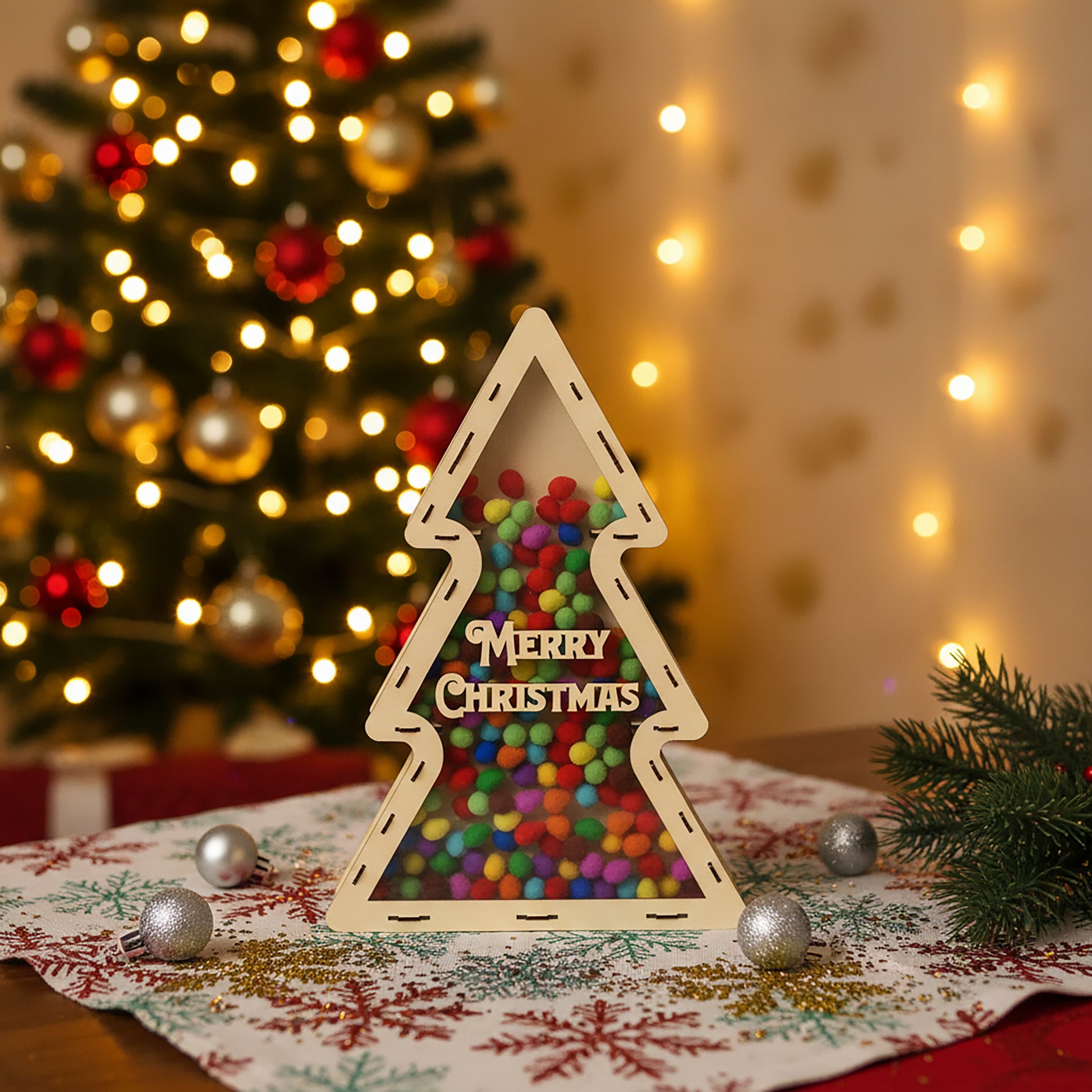 Festive laser cut Xmas Chocolate Tree holder shaped as a Christmas tree, loaded with multicolored candies visible through the clear panel, set against a glowing festive lights background.