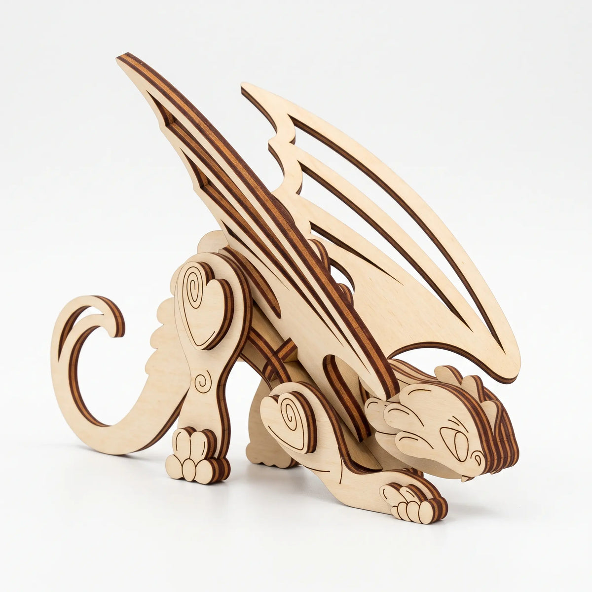 3D laser cut plywood fantasy dragon figurine with large wings and curled tail standing proudly on seamless white background.